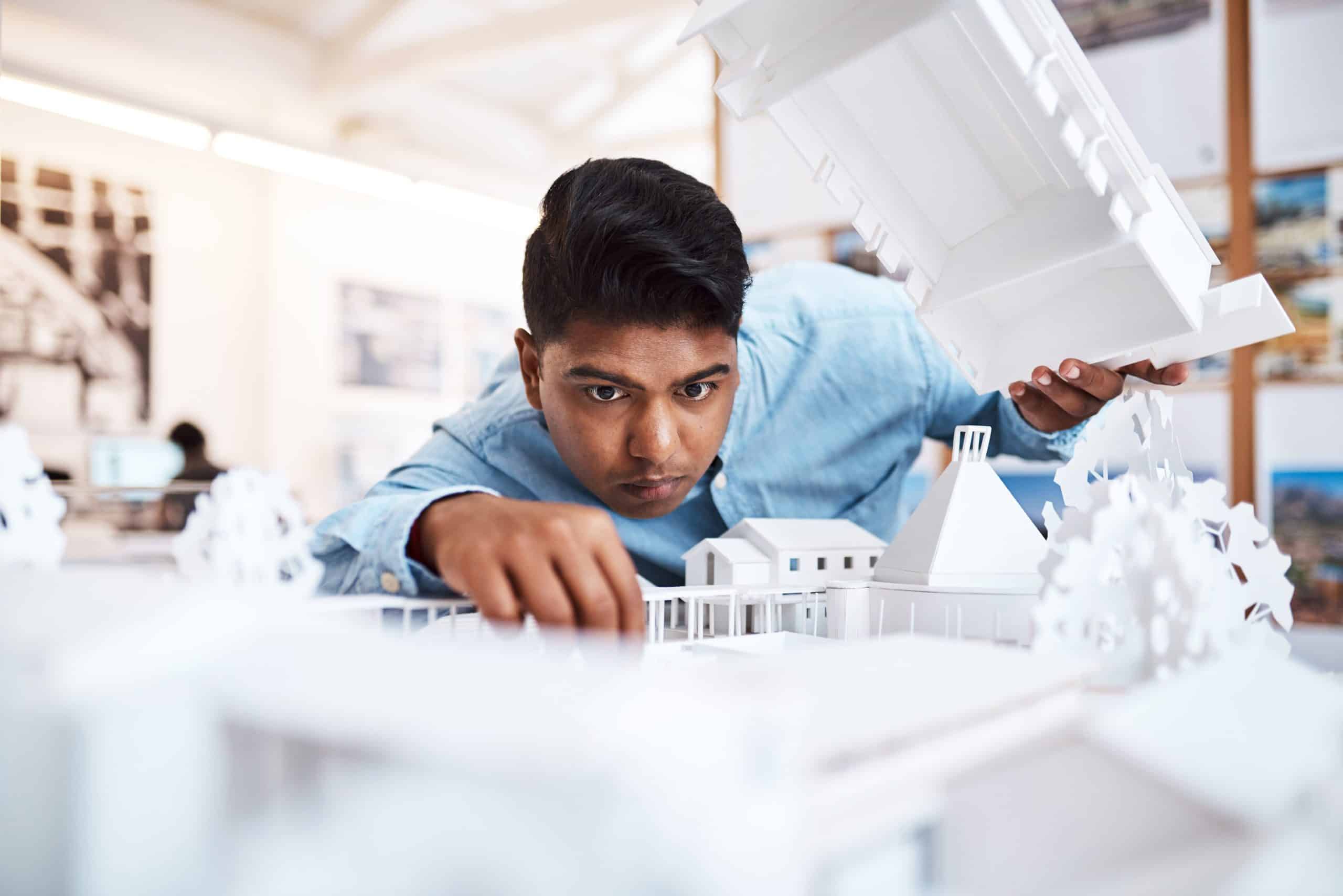 Shot of a young architect designing a building model in a modern office